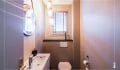 Une pièce assez grande dédiée aux toilettes qui permet d'avoir un lavabo et un miroir sublimé par trois luminaires intimistes et chaleureux.